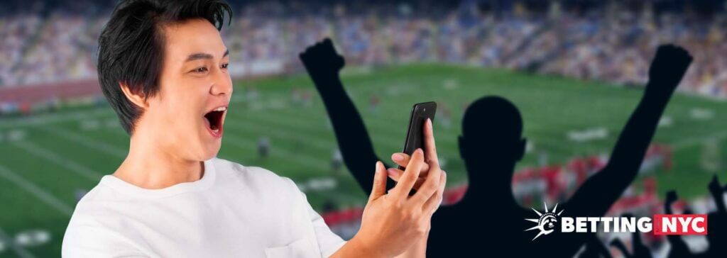 guy looks at phone with a positive grin at a football game